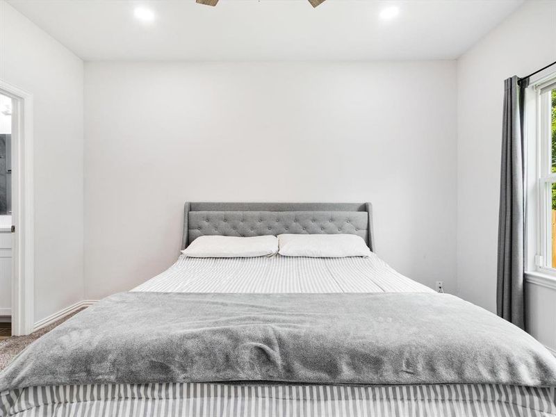 Bedroom featuring plush carpeting, a large window with natural light, recessed ceiling lighting, and a ceiling fan