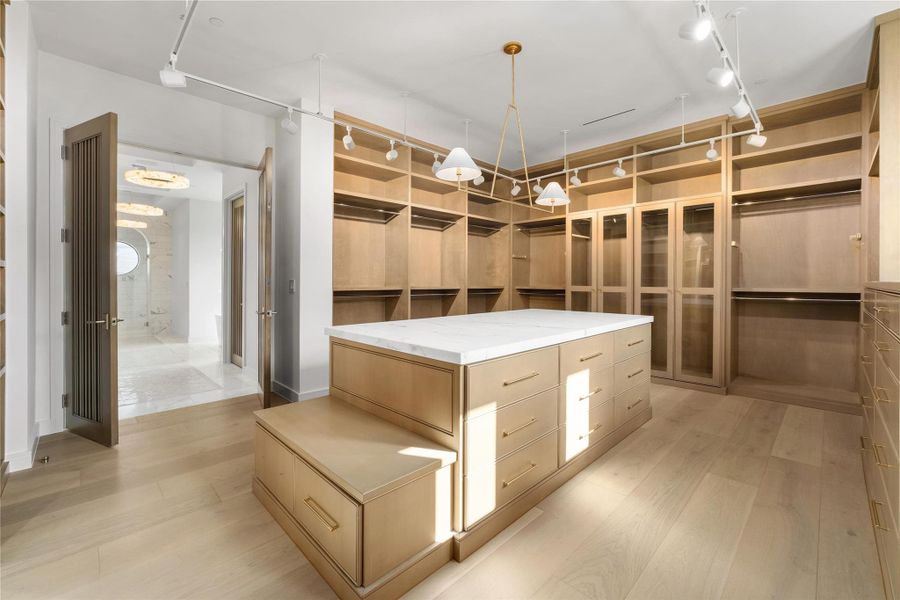 Walk-in closet with marble-top island, tall glass cabinets