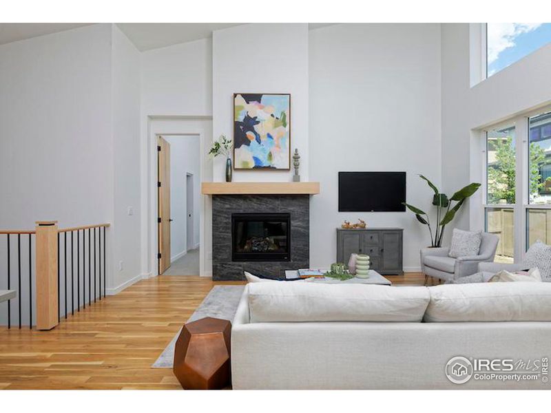 Open living room with natural light and metal railing with maple posts and handrail.