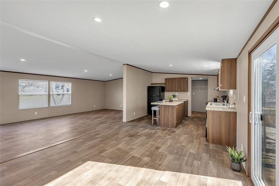 Kitchen with black refrigerator, ornamental molding, a kitchen bar, a kitchen island, and light hardwood / wood-style flooring