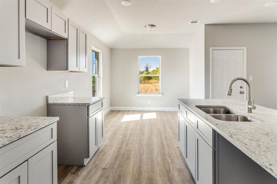 Kitchen with light stone countertops, gray cabinets, light wood-style flooring, and recessed lighting