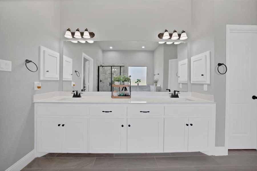 Bathroom with a stall shower, double vanity, and baseboards Bathroom with a stall shower, double vanity, and baseboards