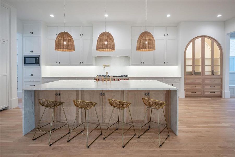 Kitchen with white cabinets, hanging light fixtures, and a spacious island