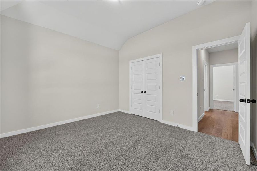 Vaulted ceiling room with grey carpeting and white trim Vaulted ceiling room with grey carpeting and white trim