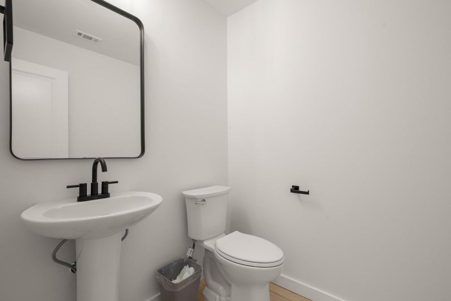 Half bath with baseboards and wood finished floors