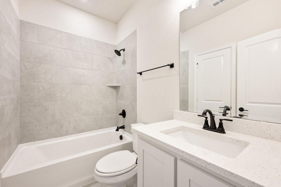Bathroom with tiled tub-shower combo, white vanity with quartz countertop, and black fixtures Bathroom with tiled tub-shower combo, white vanity with quartz countertop, and black fixtures