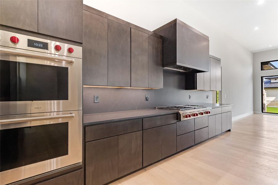 Kitchen with stainless steel appliances, tasteful backsplash, light wood-type flooring, recessed lighting, and dark brown cabinetry Kitchen with stainless steel appliances, tasteful backsplash, light wood-type flooring, recessed lighting, and dark brown cabinetry