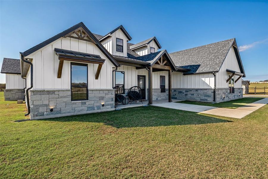 View of front of property with board and batten siding, a shingled roof, a front lawn, and stone siding View of front of property with board and batten siding, a shingled roof, a front lawn, and stone siding
