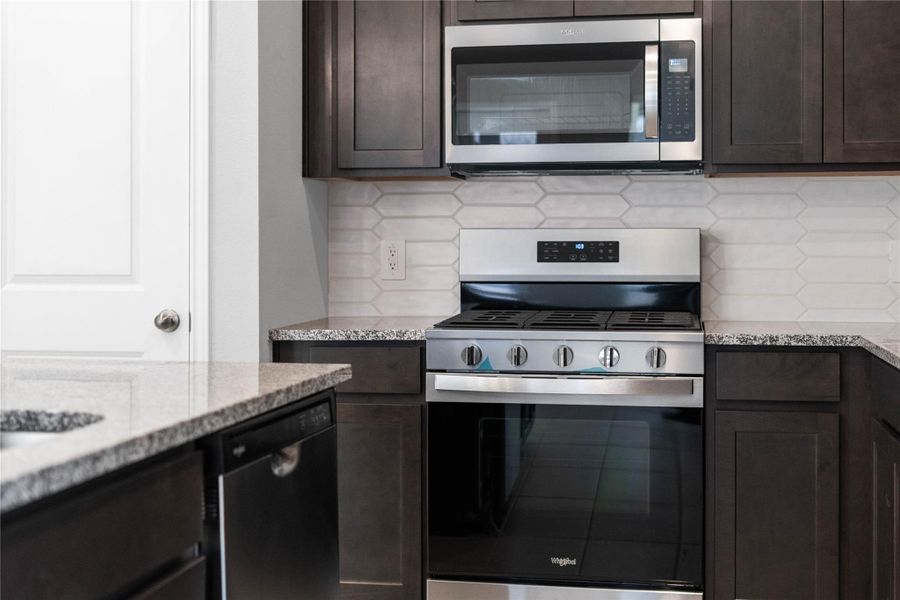 Showcased here is a Whirlpool gas range, paired with a steam microwave equipped with sensor cooking—all framed by an elegant tile backsplash.