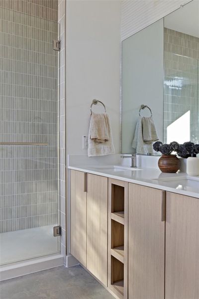 Bathroom with concrete flooring, a shower with shower door, and vanity