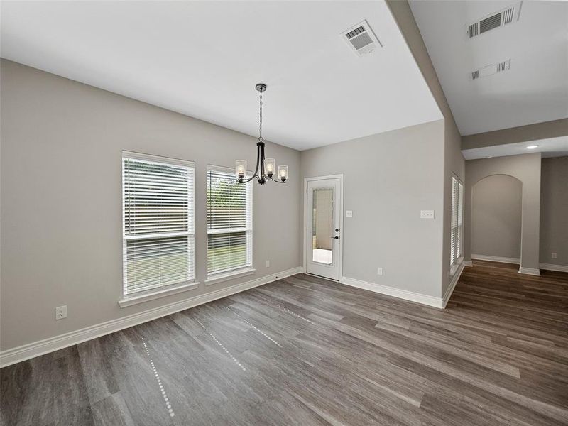 Unfurnished dining area with wood finished floors, a chandelier, and arched walkways Unfurnished dining area with wood finished floors, a chandelier, and arched walkways