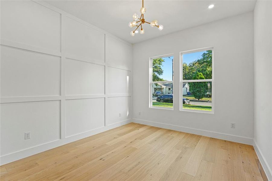 Spare room with light wood-type flooring, a chandelier, and a decorative wall