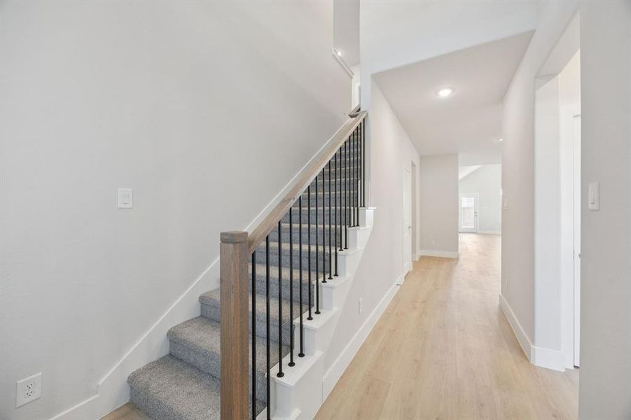 Stairway with wood finished floors and recessed lighting