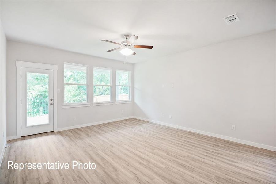 Spacious room featuring light-colored flooring, white walls, and a ceiling fan