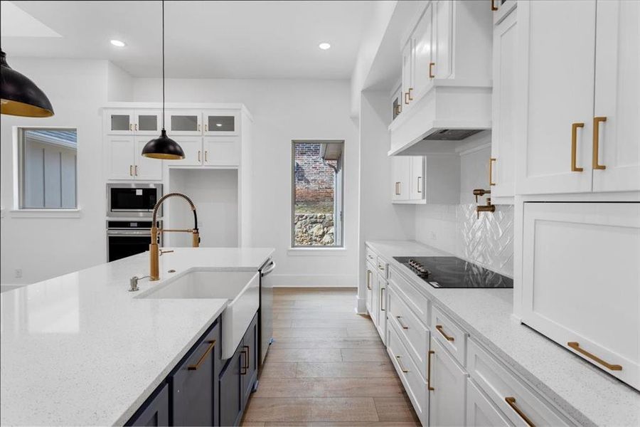 Kitchen with white cabinets, light stone counters, hanging light fixtures, and recessed lighting