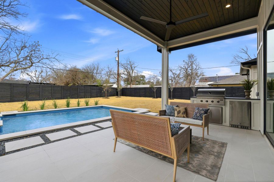 View of swimming pool featuring an outdoor kitchen with living area, patio surround, and a fenced backyard