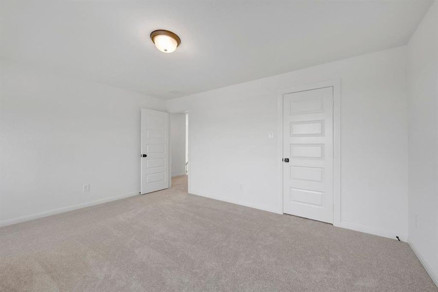 Spacious room featuring neutral carpeting, white walls, a flush-mount ceiling light with a bronze-tone base, and two white five-panel interior doors with black hardware