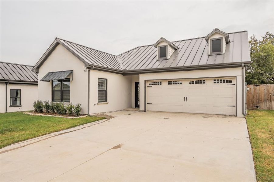 Modern inspired farmhouse with a standing seam roof, a metal roof, and concrete driveway Modern inspired farmhouse with a standing seam roof, a metal roof, and concrete driveway