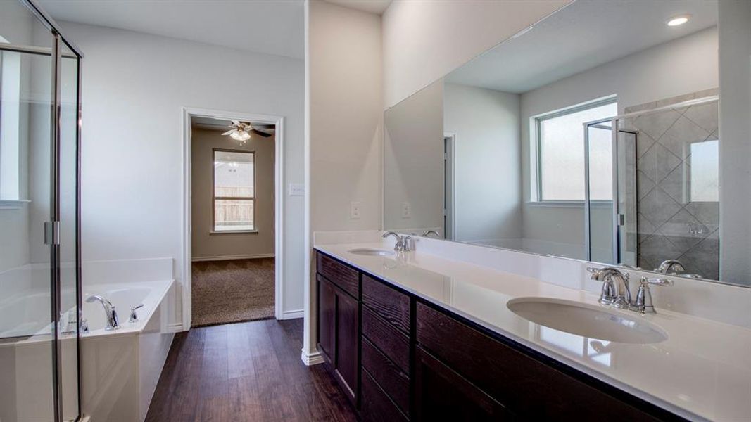 Bathroom with a stall shower, a bath, double vanity, dark wood finished floors, and a ceiling fan Bathroom with a stall shower, a bath, double vanity, dark wood finished floors, and a ceiling fan