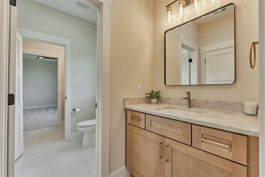 Smart Jack-and-Jill bath connecting bedrooms 3 and 4, with dual vanity areas, natural wood cabinetry, warm gold fixtures, and a private toilet/tub enclosure — function and style for the secondary suites. Smart Jack-and-Jill bath connecting bedrooms 3 and 4, with dual vanity areas, natural wood cabinetry, warm gold fixtures, and a private toilet/tub enclosure — function and style for the secondary suites.