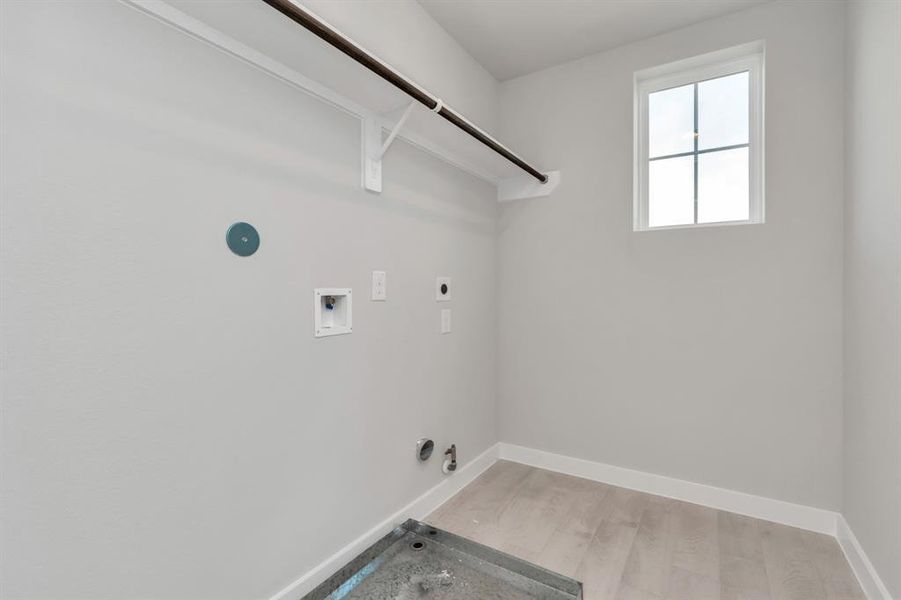 A stylish laundry room where practicality meets a contemporary aesthetic. The dark finishes lend a sophisticated touch, creating a space that is both functional and visually appealing. Both electric and gas connections available. Sample photo of completed home with similar floor plan. Actual colors and selections may vary.