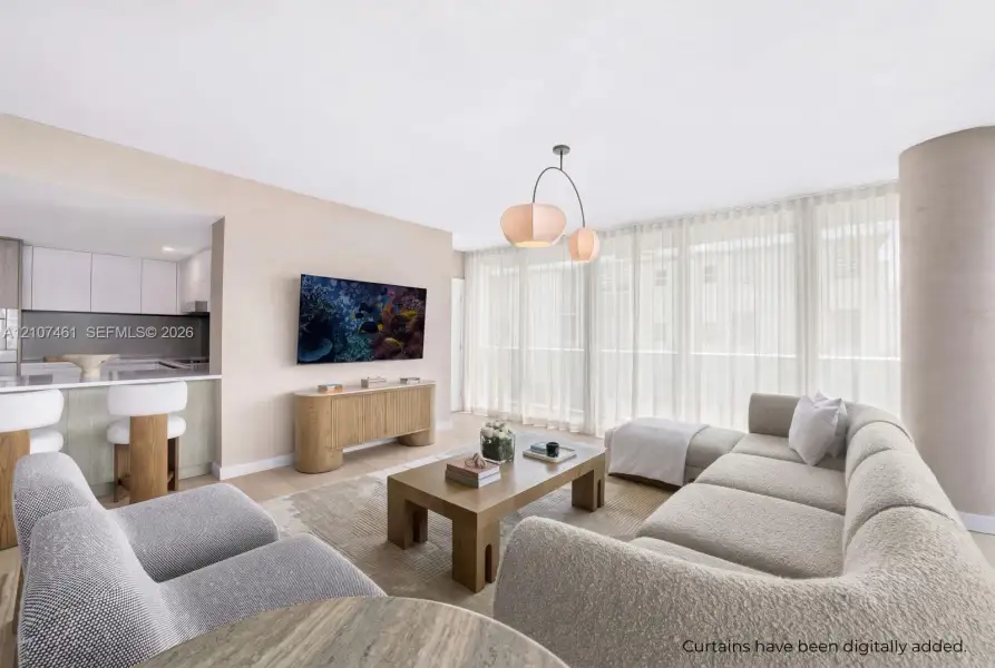Open-concept living space featuring wood-finish flooring, floor-to-ceiling windows, a modern multi-arm pendant light, and a peninsula kitchen with flat-panel cabinetry Open-concept living space featuring wood-finish flooring, floor-to-ceiling windows, a modern multi-arm pendant light, and a peninsula kitchen with flat-panel cabinetry
