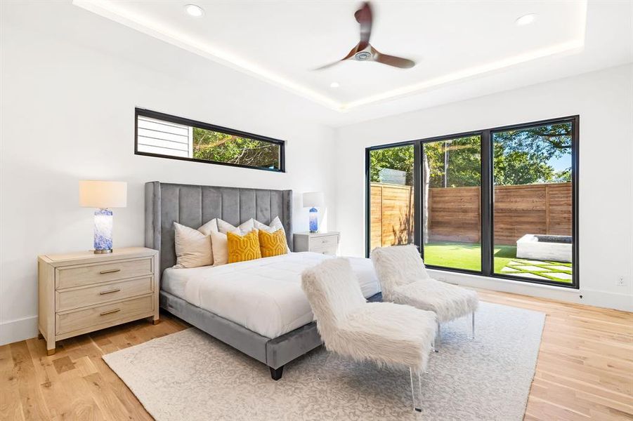 Bedroom featuring a tray ceiling, light wood finished floors, ceiling fan, and recessed lighting Bedroom featuring a tray ceiling, light wood finished floors, ceiling fan, and recessed lighting