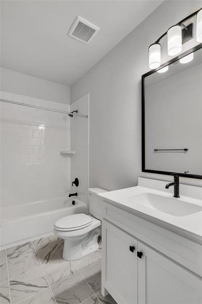 Full bathroom featuring tiled shower / bath combo, vanity, and toilet