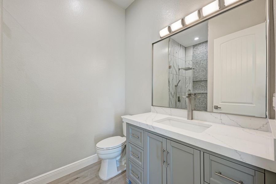 Bathroom with vanity, walk in shower, and light wood-style floors