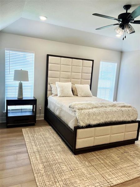 Bedroom with light wood-style flooring, baseboards, ceiling fan, lofted ceiling, and recessed lighting Bedroom with light wood-style flooring, baseboards, ceiling fan, lofted ceiling, and recessed lighting