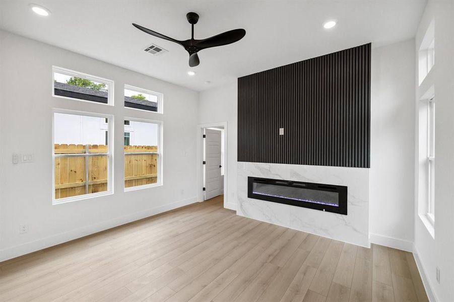 Unfurnished living room featuring a premium fireplace, ceiling fan, wood finished floors, and recessed lighting