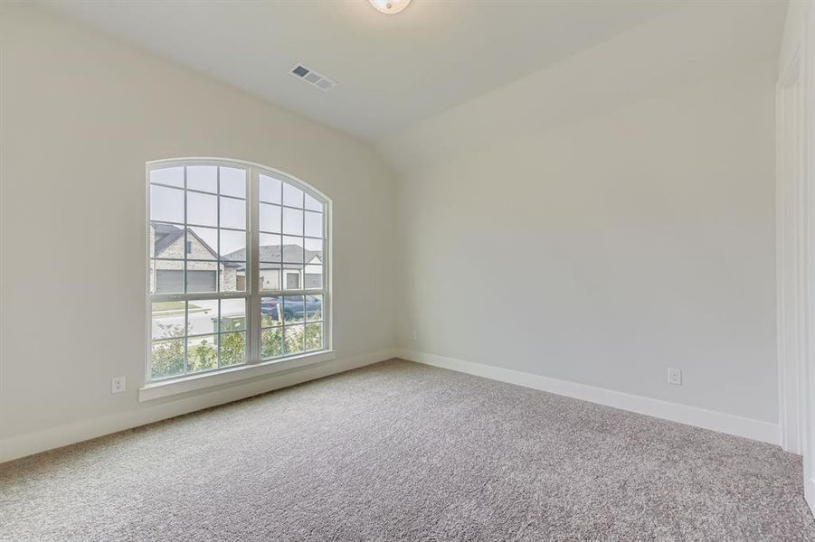 Carpeted spare room featuring lofted ceiling and baseboards