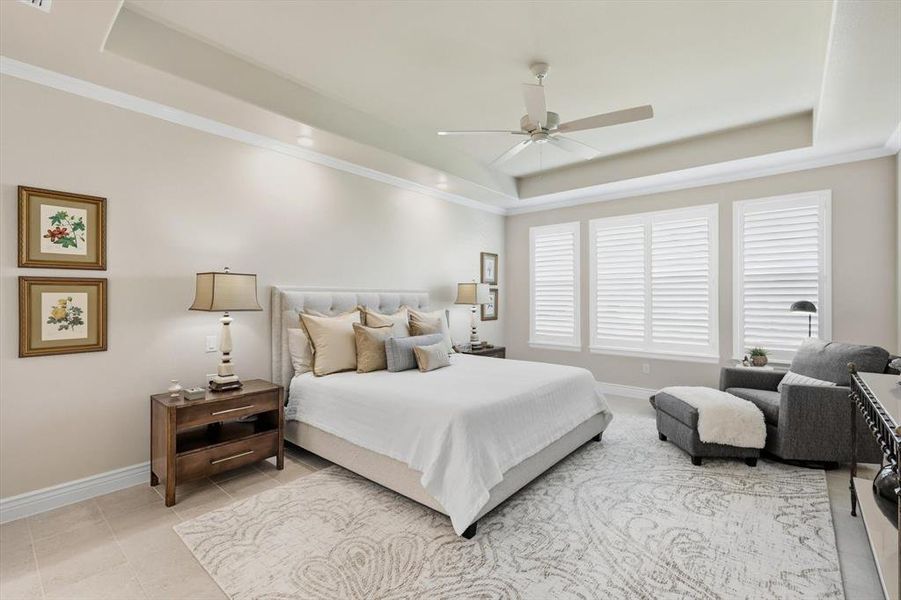 Bedroom with a raised ceiling, light tile patterned flooring, crown molding, and ceiling fan
