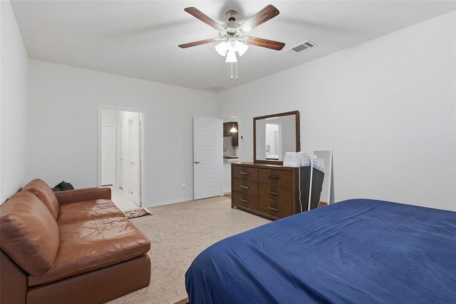 Carpeted room featuring a ceiling fan with light fixture, white walls, and a white door with a silver handle