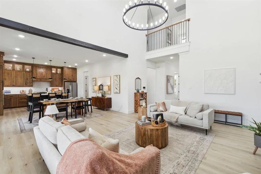 Living area featuring light wood-type flooring, a chandelier, and a high ceiling