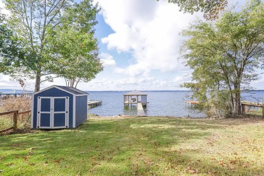 Dock featuring a water view, a lawn, and boat lift