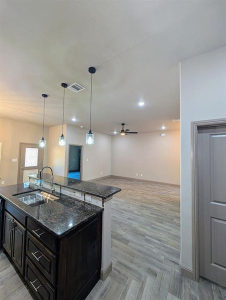 Kitchen island featuring dark cabinetry, dark stone countertop, undermount sink, and gooseneck faucet Kitchen island featuring dark cabinetry, dark stone countertop, undermount sink, and gooseneck faucet