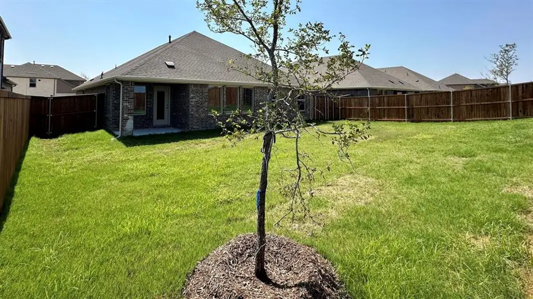 Back of house featuring brick siding, a patio, a fenced backyard, and a shingled roof