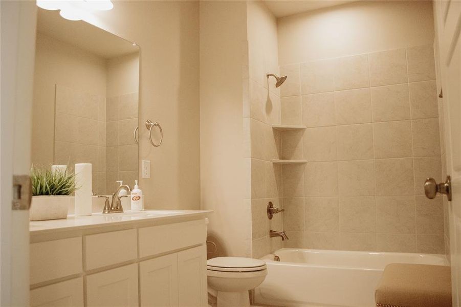 Full bathroom with tiled shower / bath combo, vanity, and toilet