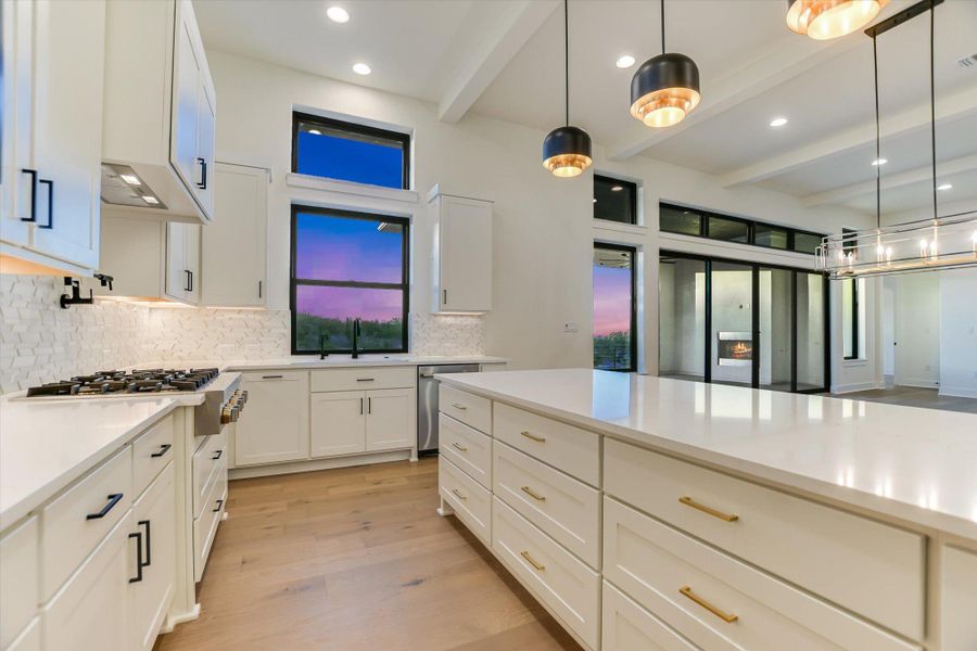 Kitchen featuring white cabinets, light wood finished floors, decorative light fixtures, and beam ceiling
