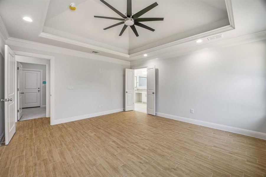 Unfurnished room with ceiling fan, wood tiled floors, recessed lighting, a tray ceiling, and crown molding Unfurnished room with ceiling fan, wood tiled floors, recessed lighting, a tray ceiling, and crown molding