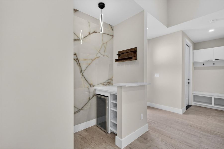 Chic and modern nook featuring a stylish wet bar, accented by elegant marble backsplash and sleek pendant lighting, perfect for entertaining.