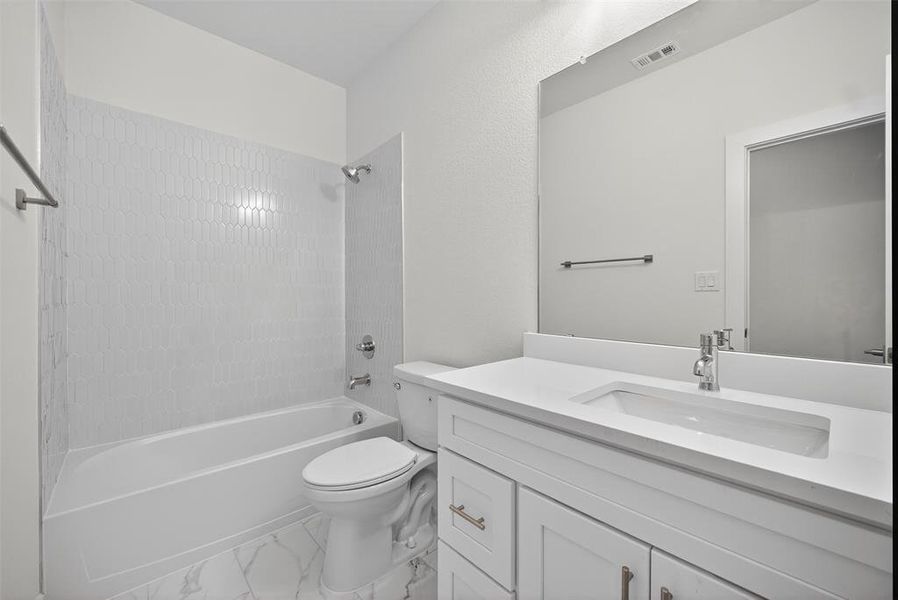 Full bath with bathing tub / shower combination, vanity, and light marble finish flooring Full bath with bathing tub / shower combination, vanity, and light marble finish flooring