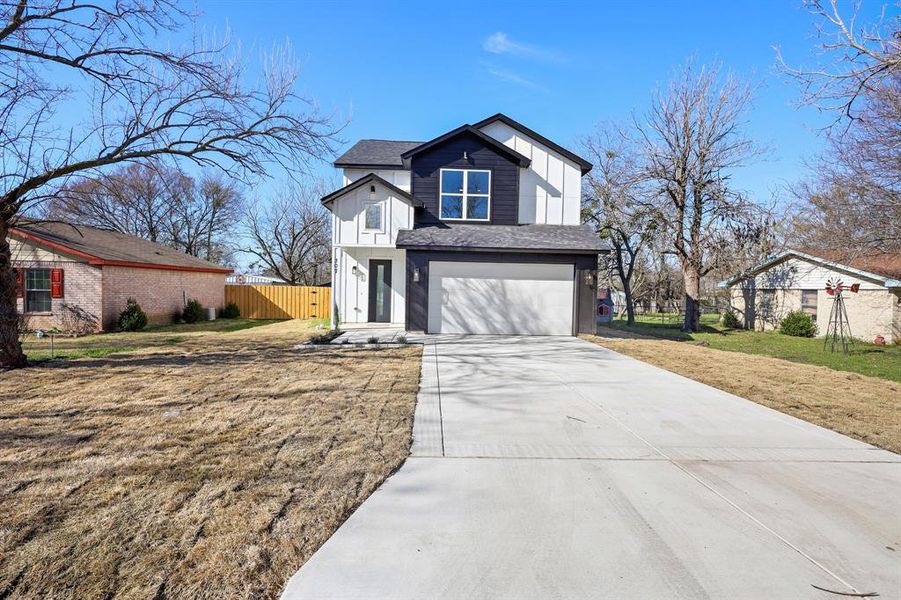 View of front facade featuring a front lawn and a garage