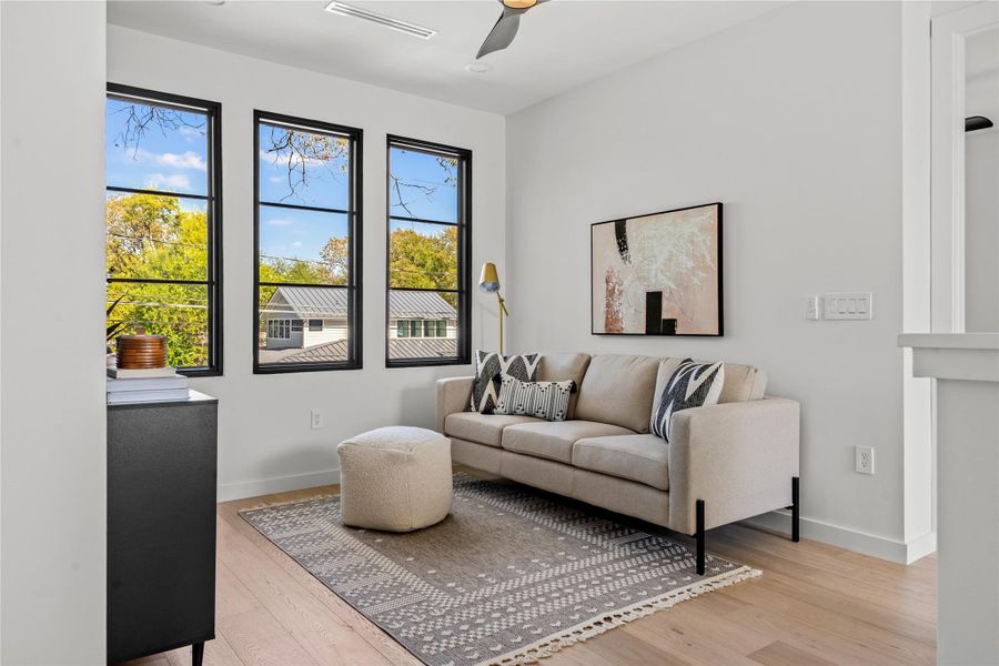 Living area with light wood-style floors and a ceiling fan