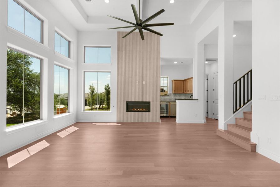 Natural light floods this living space, featuring high ceilings and a striking fireplace.
