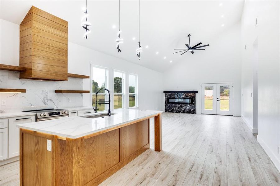 Kitchen featuring open shelves, white cabinets, healthy amount of natural light, light wood-type flooring, and high vaulted ceiling Kitchen featuring open shelves, white cabinets, healthy amount of natural light, light wood-type flooring, and high vaulted ceiling