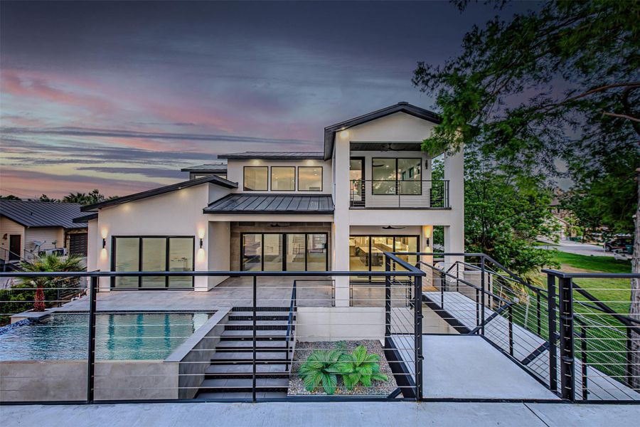 Rear view of property with metal roof, an outdoor pool, a balcony, a patio, and stucco siding