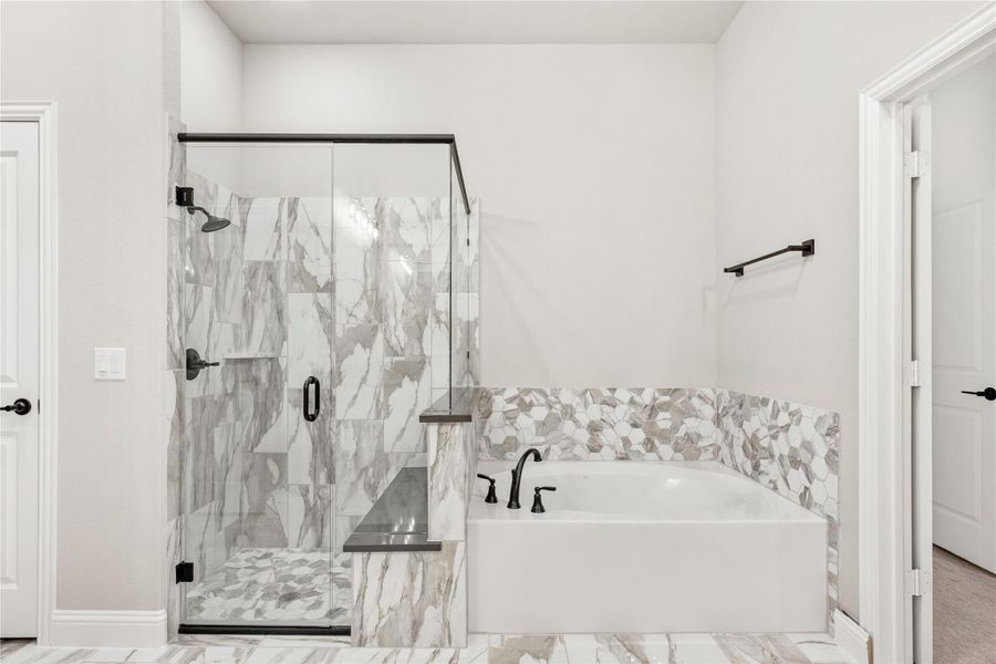 Master bathroom with glass-enclosed marble tile shower, soaking tub with hexagon tile surround, and black fixtures