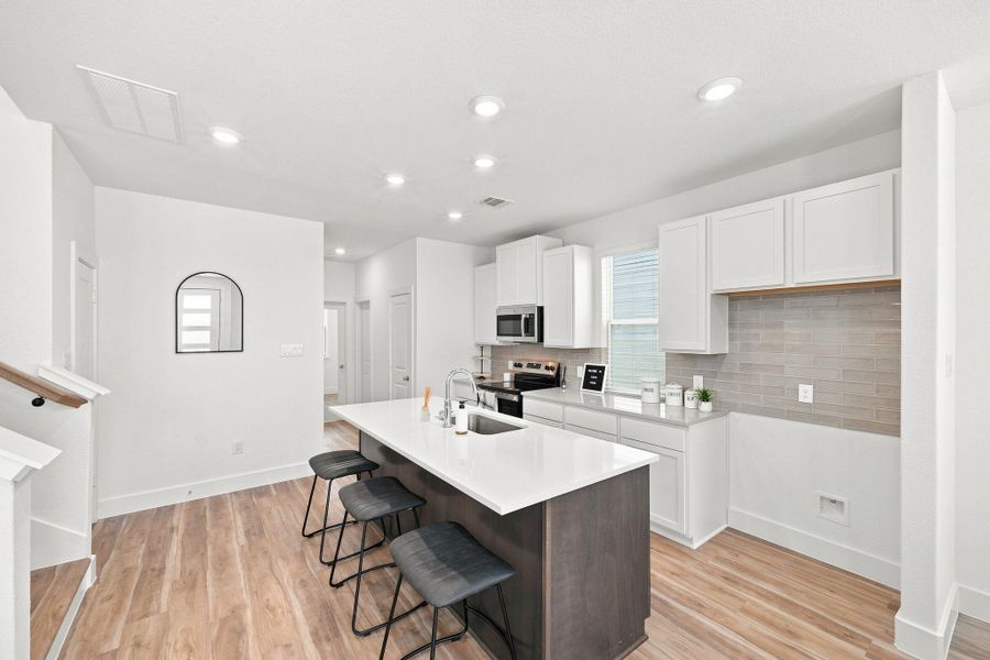 Spacious kitchen featuring an oversized quartz island with seating for three, contrasting cabinetry, and abundant counter and storage space. Spacious kitchen featuring an oversized quartz island with seating for three, contrasting cabinetry, and abundant counter and storage space.
